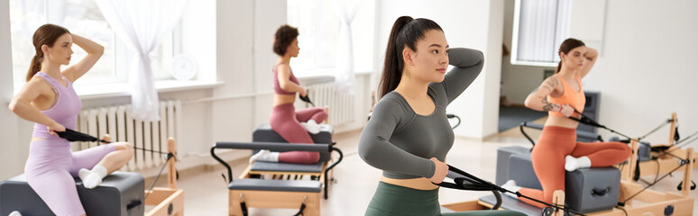 Group of sporty women practicing pilates exercises in a room.