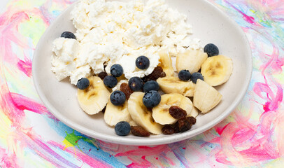Bananas with blueberries, cottage cheese and raisins slices in a plate. Appetizing bananas with black berries