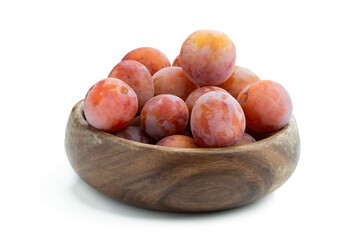 Ripe purple plums in wooden bowl isolated on white background