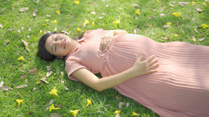 A portrait of happy Asian pregnant woman walking in public garden park on vacation. Love of mother. Having a baby. Family people lifestyle.