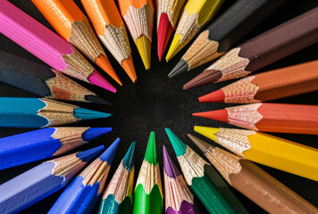 Naklejka premium Colored pencils in circle on black background