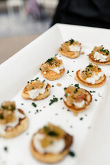 Appetizers on a white rectangular plate garnished with herbs