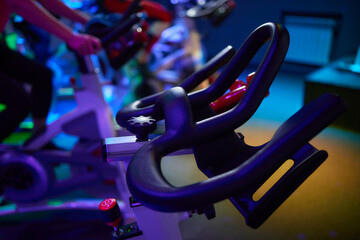 Row of exercise bikes in gym under electric blue lighting