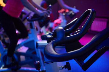 Row of exercise bikes in gym under electric blue lighting