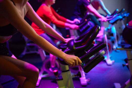 Woman cycling on pink exercise bike with magenta bicycle handlebar in gym