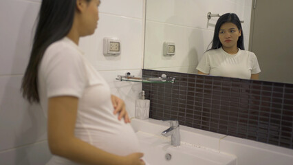 A portrait of happy Asian pregnant woman in toilet,  bathroom or restroom with basin. Having a baby. Family people lifestyle. Mom love.