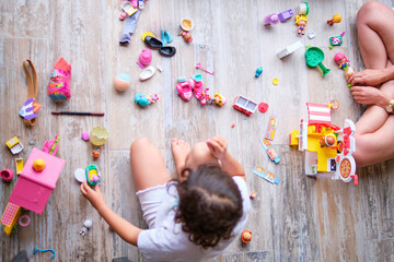 image from above of girl sitting on the floor playing with dolls