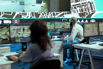 Diverse employees giving gps coordinates to couriers via satellite navigation, using city map to...
