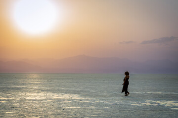 Women figure in a sunset time on Karum white salt lake surface, Danakil Depression desert, Afar region, Ethiopia
