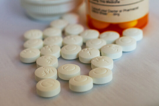 Generic metformin dispensed from a pharmacy 500 mg tablets on a white background with orange prescription bottle in background.
