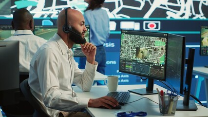 Middle eastern call center operator gives directions to the courier, avoid traffic by monitoring radar CCTV surveillance and a satellite city map. Employee helps with express delivery. Camera A.