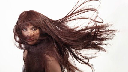 Brunette beauty model with healthy long hair flying against white background