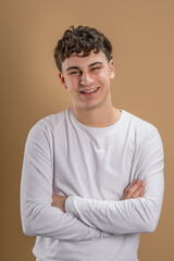 Portrait of one caucasian man 20 years old looking to the camera in front of almond color studio background smiling wearing casual shirt copy space