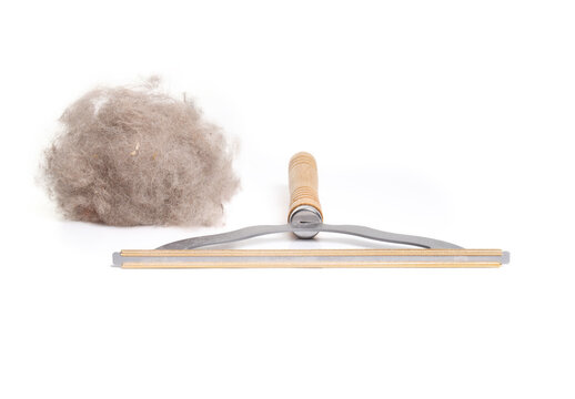 Carpet brush with lint pile from cleaning. Carpet rake or comb can be used to remove stubborn pet hair from fabrics, carpet or furniture. Cleaning gadget. Selective focus. White background.