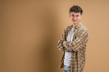 Portrait of one caucasian man 20 years old looking to the camera in front of almond color studio...