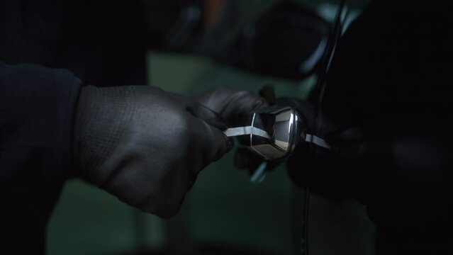 The creepy thief with wearing black mask using tool to break unlock the door's handle of vehicle, robber opening the car's door to steal, car security to prevent the crimination.
