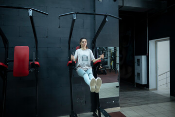 Woman Working Out On Ab Crunch Machine In Modern Gym, doing abdominals exercises leg raises