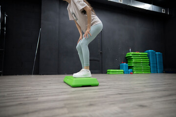Female person Stepping Up On Green Aerobic Platform During Workout