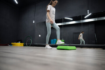 Female person Stepping Up On Green Aerobic Platform During Workout