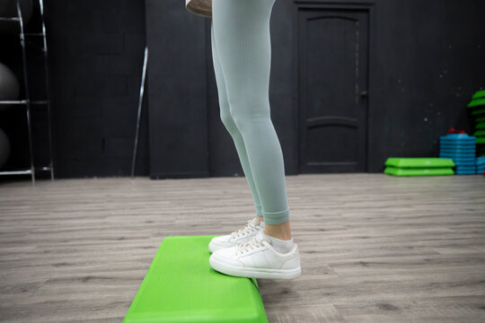 Female person Stepping Up On Green Aerobic Platform During Workout