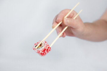 male hand with chopsticks holding sushi roll isolated on white background