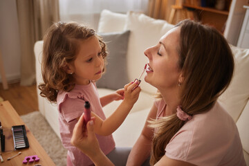 Mother and daughter doing makeup sitting in the living room