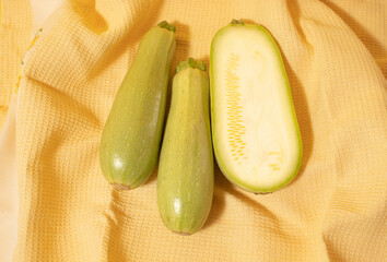 Fresh green zucchini on yellow background.