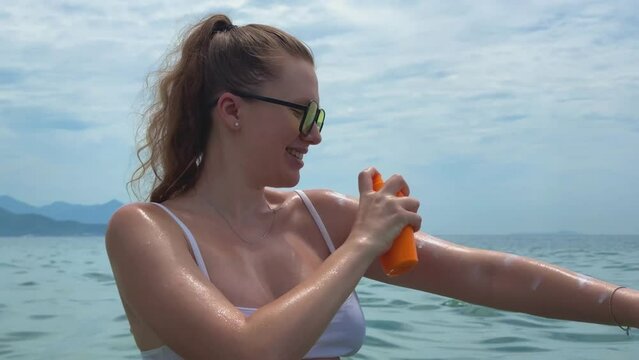 Young woman using, applying sunscreen cream on skin at summer sunny day near swimming pool