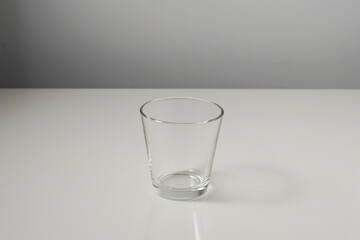 An empty clear glass cup with reflections, isolated on white background