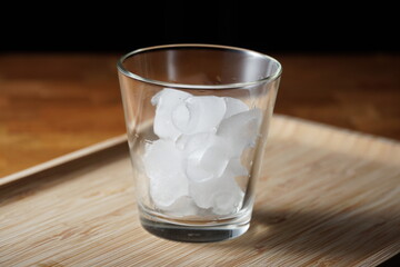 A cup of ice in a wooden tray.