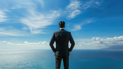 Businessman standing with his back to the camera, facing a vast sea view