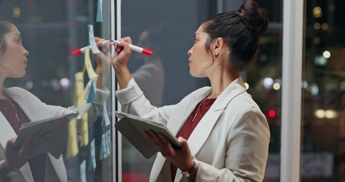 Business woman, writing and night with tablet on glass board for schedule planning, tasks or brainstorming at office. Young female person or employee taking notes with technology for project deadline