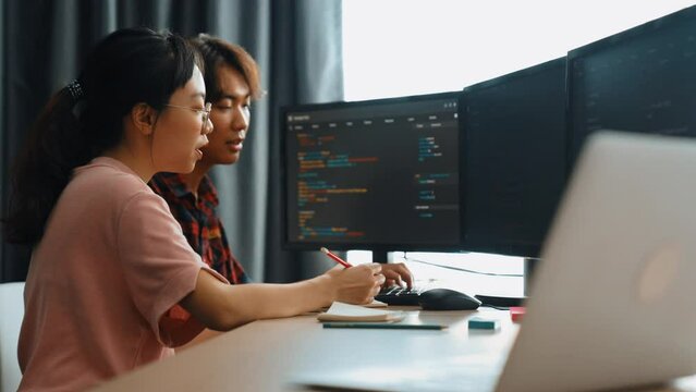 Slow motion back end software developer engineer for computer programming working together on debugging writing computing code, solving complex algorithms display on monitor in office. Burgeoning