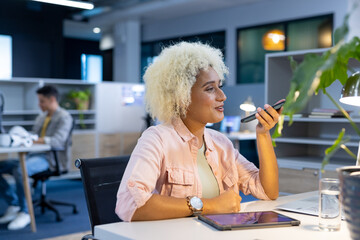 Biracial woman using smartphone in modern office for business