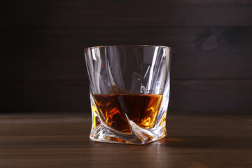 Delicious liqueur in glass on wooden table