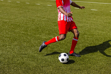 African American fitness trainer wearing red and white sportswear playing soccer, copy space