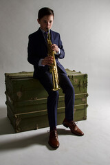 Young male saxophonist playing his instrument while seated on a green box 