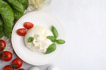 Delicious burrata cheese, tomatoes, basil and spinach on light table, flat lay. Space for text