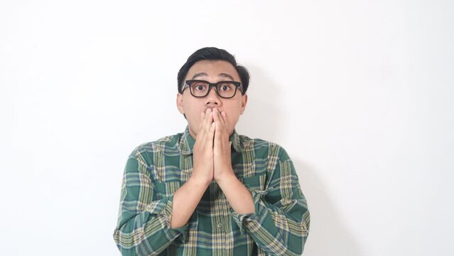 Surprised Look: A portrait of a man with glasses showing astonishment with his mouth wide open, hand covering mouth against a white background