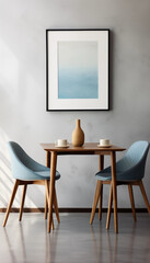 Two blue chairs and a wooden table with a vase and two cups on it in front of a gray wall with a painting of the ocean above it