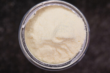 View from the top of a can with whole milk powder. Black surface.
