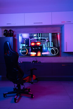 Gaming chair for video games in neon room with video streaming on screen, copy space