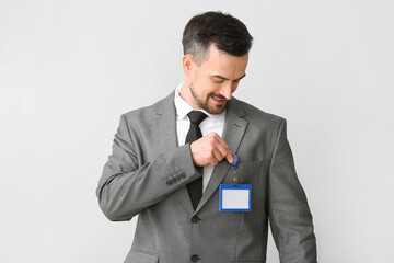 Young businessman with blank badge on light background