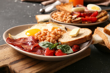 Plates of tasty English breakfast on black background
