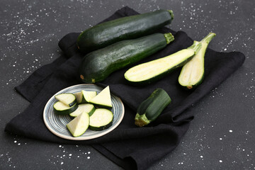 Fresh green zucchini and plate with slices on black background