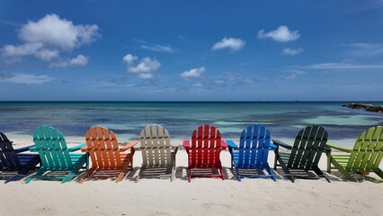 Rear view of assorted colored beach chairs facing a tropical ocean.