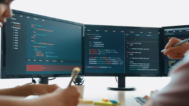 Slow motion back end software developer engineer for computer programming working together on debugging writing computing code, solving complex algorithms display on monitor in office. Burgeoning