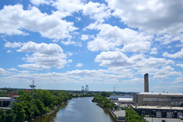 Fototapeta premium Bright blue sky with soft fluffy clouds. Building in the distance. 