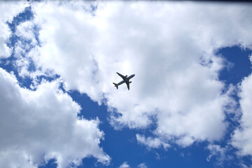 An airplane is in a blue sky with beautiful white clouds. 