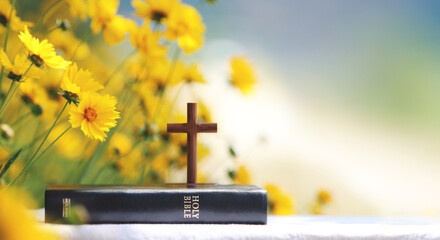 Cross of Jesus Christ, holy bible, beautiful yellow flowers and prayer and worship background
